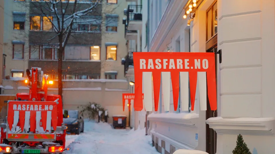Rasfare varselskilt ved en bygård om vinteren